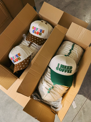 Multiple coffee themed hats in boxes.
