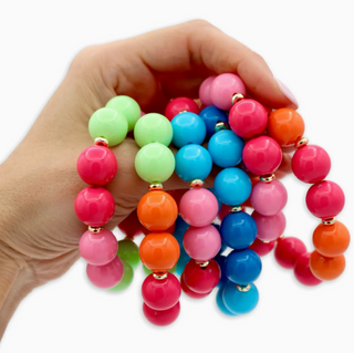Colorful beaded bracelets held in a hand on a white background