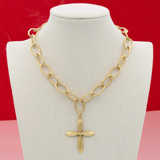 Gold chain necklace with a cross pendant on a mannequin bust against a red background