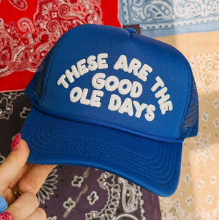 Blue cap with 'These are the good ole days' text held against a patterned background