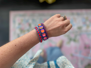 Hand wearing colorful bracelets with a blurred background