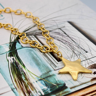 Gold chain necklace with a star pendant on a magazine background