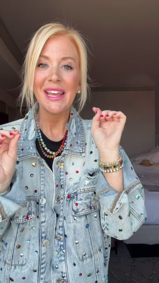 Southern Quirks Try on Video for an oversized denim jacket that is embellished with colorful gemstones.  Model pairs this jacket with a black set and colorful jewelry.  Compliment Magnet statement piece.